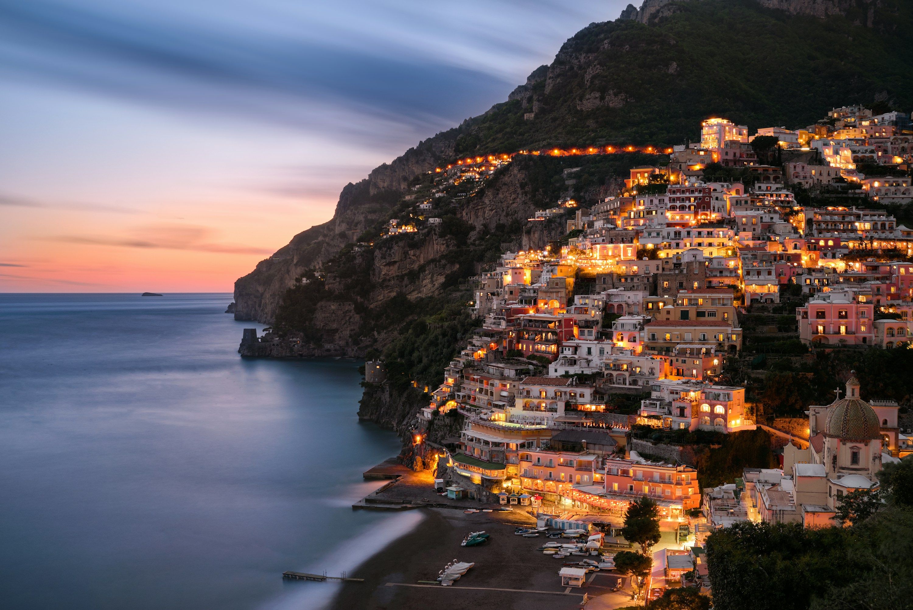 Positano on the Amalfi Coast at dusk, the hillside lit above the sea